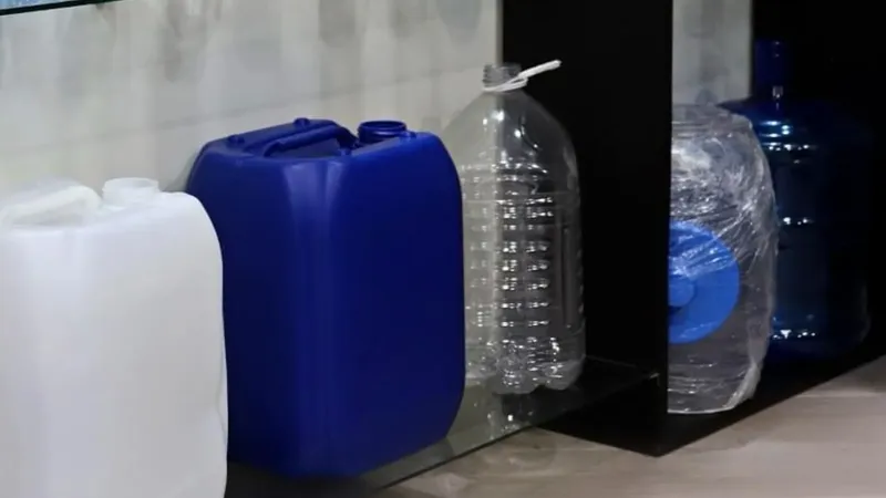 Anaquel con garrafas de plástico blanca y azul, una garrafa transparente y garrafones de 20 litros